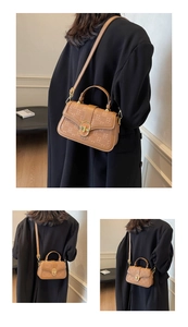 Detail view of brown embossed leather square bag with gold rotary clasp and shoulder strap