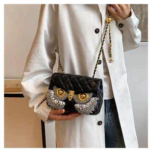 Detail of owl chain bag featuring faux pearl and rhinestone embellishments on black leather