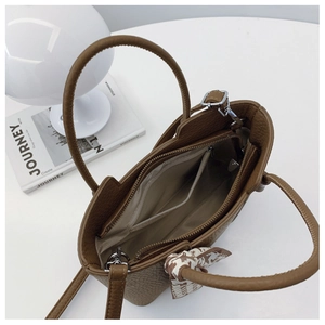 Detail of brown litchi leather bucket bag with inner compartments and silk scarf