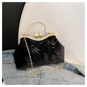 Macro detail of black velvet handbag with bamboo embossing and gold pearl clasp