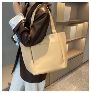 Detail of minimalist beige tote bag with litchi texture and wide shoulder strap