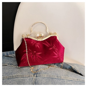 Detail of red velvet handbag with bamboo leaf embroidery and luxury pearl clasp