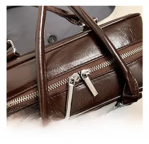 Close-up of dual zippers and sturdy top handles on a vintage brown leather bag