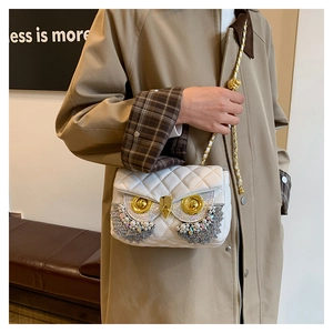 Detailed close-up of white quilted crossbody bag with ornate owl-shaped pearl hardware