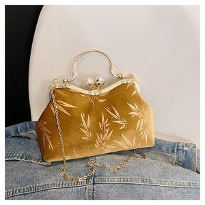 Detail of velvet bag featuring gold bamboo leaf patterns and large pearl clasp accents