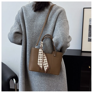 Detail of brown lychee grain leather tote with a stylish houndstooth silk scarf handle
