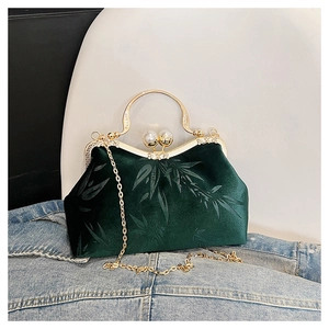 Detail of dark green velvet handbag with bamboo patterns and pearl clasp closure
