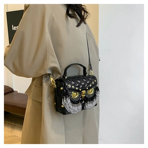 Detail of owl crossbody bag featuring black quilted texture and golden rivet tassels