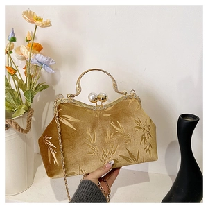 Close-up of golden velvet evening bag with bamboo leaf embossing and pearl clasp lock