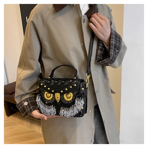 Close-up of owl-shaped crossbody bag with quilted black patent leather and fringe detail