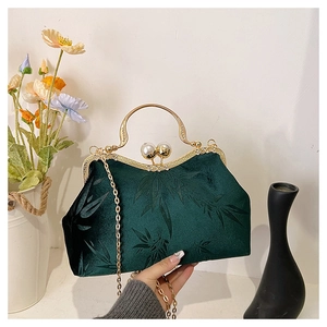 Detail of dark green velvet bag with bamboo pattern, metal handle and pearl clasp