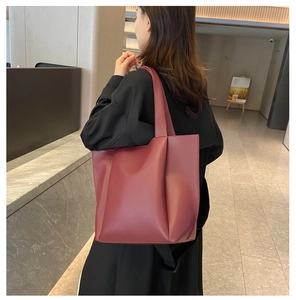 Close-up of a burgundy leather tote bag with a soft texture carried by a model