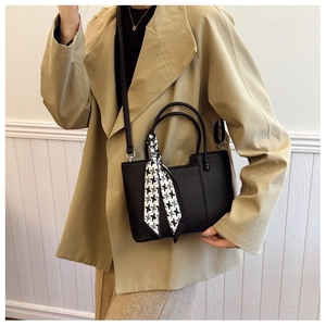 Detail of black pebbled leather tote bag with stylish patterned silk scarf on handle