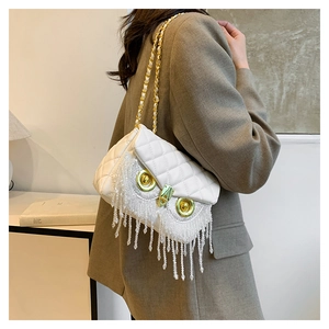 Detail of owl-shaped crossbody bag with white quilted pattern and bead tassel fringe