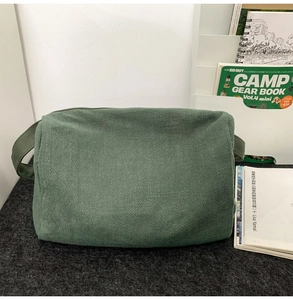 Détail du sac à bandoulière en toile vert foncé avec sangle large et texture tissée