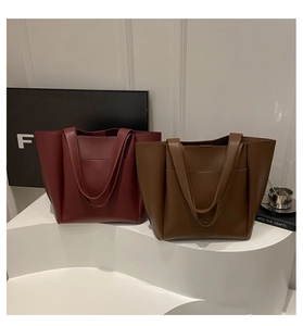 Detail view of large matte leather tote bags in burgundy and caramel brown on display
