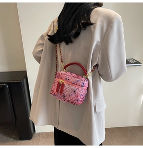 Detail of pink tweed vanity bag with gold chain strap worn over a grey blazer