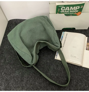 Vue de dessus d'un sac bandoulière en toile vert foncé avec fermeture sur feutre gris