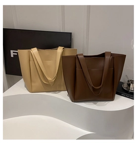 Detail view of beige and dark brown minimalist tote bags with front pockets on display