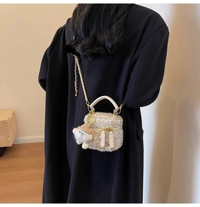 Detail of beige tweed mini crossbody bag with golden chain and plush doll charm