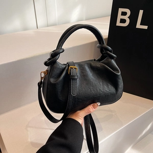 Borsa a mano a nuvola nera a pieghe alla moda con manico a nodo e dettagli in oro su podio