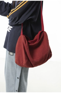 Détail du sac bandoulière en toile rouge foncé montrant le coton lavé et la large sangle
