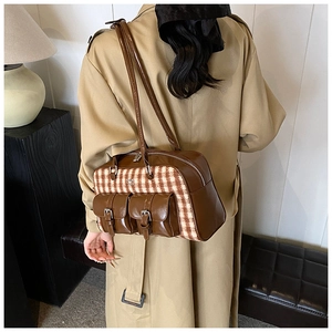 Detail of vintage houndstooth shoulder bag with leather straps on a khaki trench coat