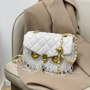 White quilted owl crossbody bag with crystal fringe and golden chain strap on beige coat