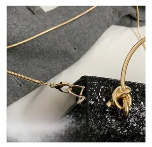 Detail of black sequin evening bag with gold ring handle and snake chain strap