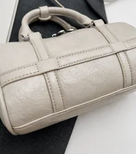 Detailed close-up of soft pleated texture and stitching on beige bowling bag