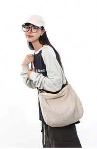 Détail d'un grand sac bandoulière en toile beige avec bandoulière large sur mannequin