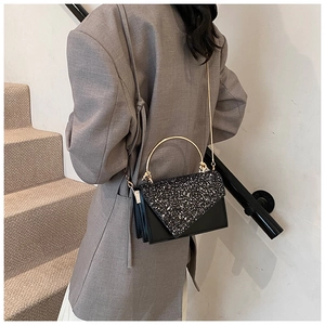 Detail of black sequined flap bag with gold semi-circle handle and chain strap