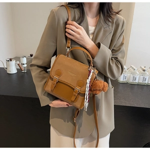 Dettagli dello zaino vintage marrone con ciondolo a forma di orsetto e cinturino in tessuto