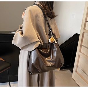 Detail of soft brown leather hobo bag with baseball charm and fashion brand logo
