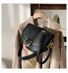 Détail d'un sac besace en cuir noir avec boucle en D dorée et bandoulière élégante