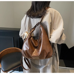 Borsa tote vintage marrone indossata da modella con tracolla e ciondolo decorativo