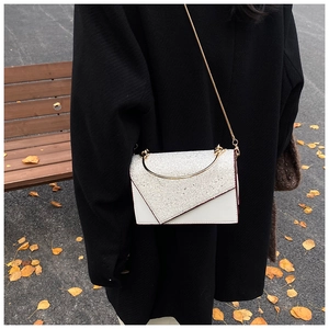 Detail of white leather shoulder bag with silver sequins and gold metal handle