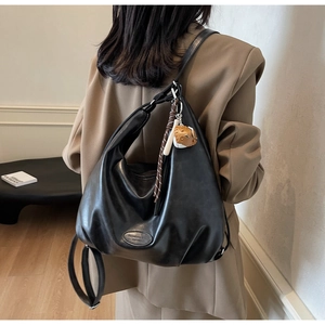 Dettaglio della borsa tote in morbida pelle nera con logo e ciondolo con nappa