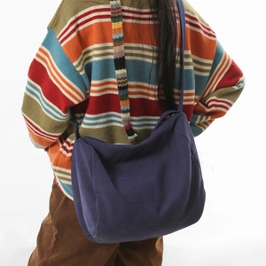 Grand sac bandoulière en toile bleu marine avec large sangle rayée porté par mannequin
