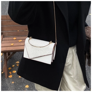 Detail of white sequined crossbody bag with geometric V-flap and gold chain strap