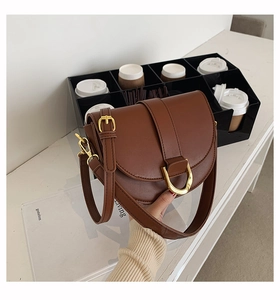 Détail du sac besace marron avec boucles dorées et large bandoulière ajustable