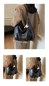 Dettaglio borsa hobo nera vintage lucida con ciondolo a forma di mini mazza da baseball