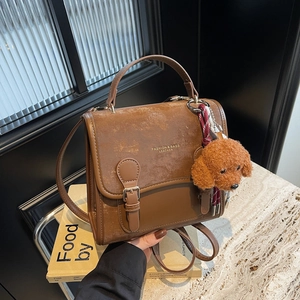 Zaino vintage in pelle marrone con cuciture a contrasto e ciondolo a cane in peluche su pietra