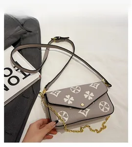 Close-up of taupe textured leather crossbody bag with floral pattern and gold chain strap