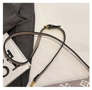 Detail of adjustable litchi texture leather shoulder strap with gold-tone buckle