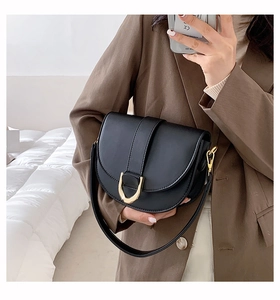 Selfie miroir montrant un sac selle noir mat avec une grande boucle en fer à cheval dorée