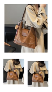 Detail of vintage brown leather tote bag with FASHION & BAGS print and plush bear charm
