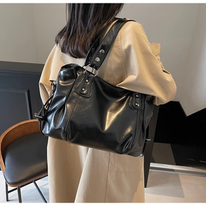 Détail du sac fourre-tout noir en cuir PU avec rivets argentés et texture plissée