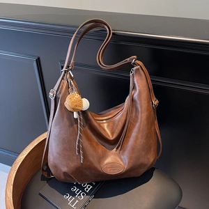 Retro deep brown hobo tote bag with leather texture and cute mushroom charm on a chair