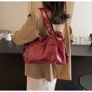 Détail du sac cabas en cuir bordeaux avec rivets métalliques et poche latérale à fermeture éclair